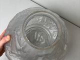 a person holding a clear glass vase on a table