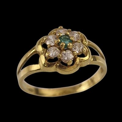 gros plan d'une bague en or avec des pierres vertes et blanches