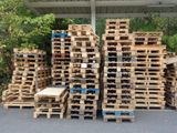many wooden pallets stacked up on the side of the road