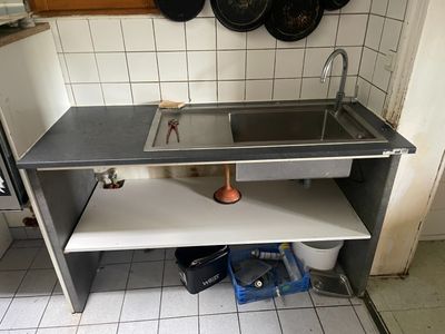 un évier de cuisine avec des casseroles et des poêles accrochées au mur