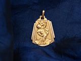 a gold pendant with an image of a woman holding a child