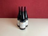 two bottles of wine sitting on a table with a red wall in the background
