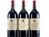 three bottles of red wine are lined up on a white surface