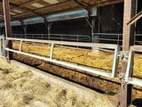 une grange remplie de foin, avec une vache à l'intérieur