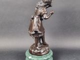 bronze statue of a girl holding a bird on a marble base