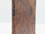 an old book with a brown cover sitting on top of a white surface