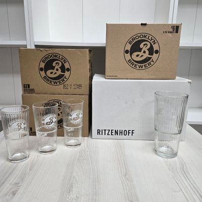 four glasses sitting on a table next to a box of beer