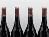six bottles of red wine lined up in a row on a table