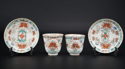 trois tasses et soucoupes en porcelaine chinoise posées sur des socles, sur fond noir