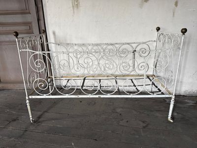 a white iron bench sitting on the floor in front of a white wall