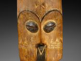 un gros plan d'un masque en bois posé sur un socle