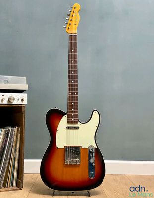une guitare électrique posée sur un parquet en bois massif, à côté d'un tourne-disque