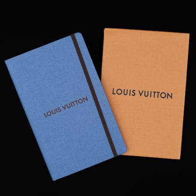 two notebooks with the words louis vuitton on them