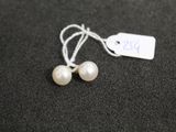 une paire de boucles d'oreilles en perles blanches avec une étiquette de prix sur un fond noir
