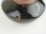 a black and brown vase with a gold decoration on it