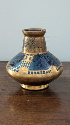a blue and gold vase sitting on a wooden table