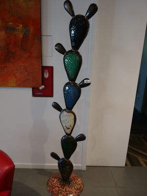 a tall glass cactus plant in the middle of a living room