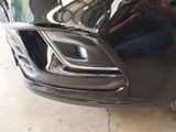 a close up of a car ' s front bumper with a reflection of a man in the mirror