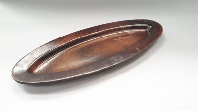a brown oval plate on a table with a white background