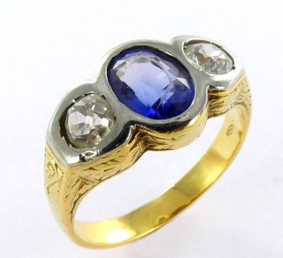 a close up of a gold ring with a blue stone and two diamonds