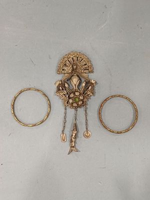 three gold rings and a broochet on a white surface