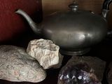 rocks and a teapot sit on a shelf next to a teapot