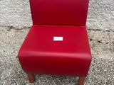 une chaise rouge posée devant un mur sur lequel est accrochée une étiquette