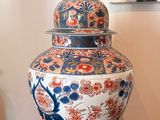 un grand vase posé sur une table en bois, avec un tableau accroché au mur derrière lui