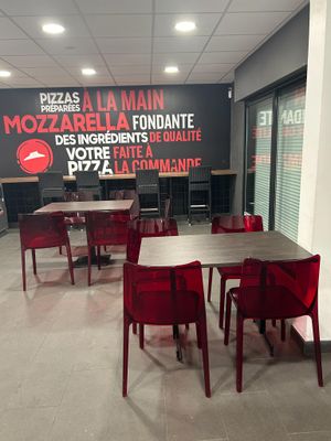 des tables et des chaises dans un restaurant où est accrochée une grande enseigne au mur