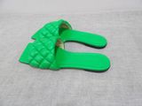 a pair of green sandals on a bed with a white sheet