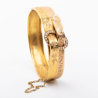 a close up of a gold bracelet with a chain on a white background