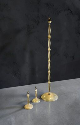 une paire de bougeoirs en laiton posés sur une table, sur fond noir