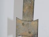 an old iron cross on a wooden stand against a white wall