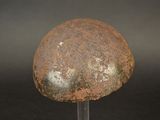 rusty helmet on a metal stand against a black background