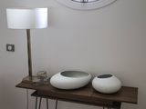 deux vases blancs posés sur une table, avec une horloge accrochée au mur