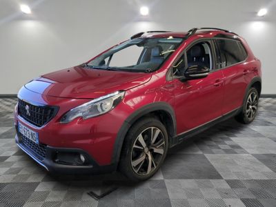 une voiture rouge est garée dans une pièce au sol en damier