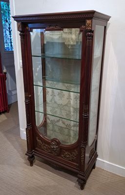 une vitrine avec une porte vitrée, dans un coin de la pièce