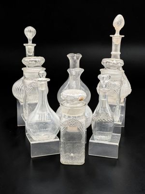 trois vases en verre transparent et un bougeoir posés sur une surface noire