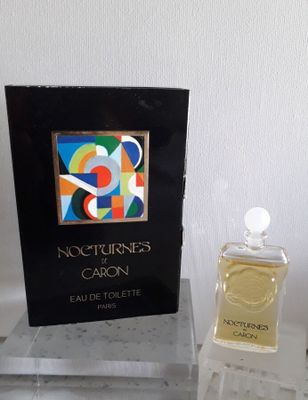 un flacon de parfum posé sur une table à côté d'un livre