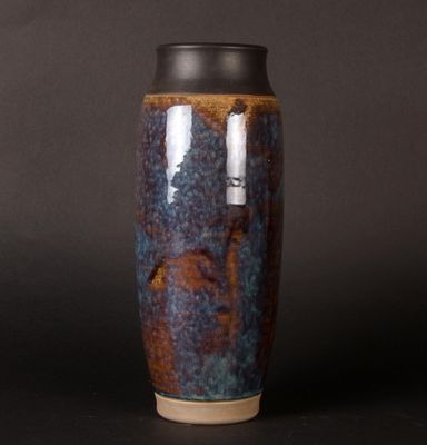 a blue and brown vase on a black surface