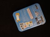 a blue tin with stickers on it sitting on a black surface