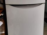 un réfrigérateur blanc posé dans un garage à côté d'autres appareils électroménagers