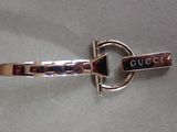 silver bracelet with gucci logo on it sitting on a table