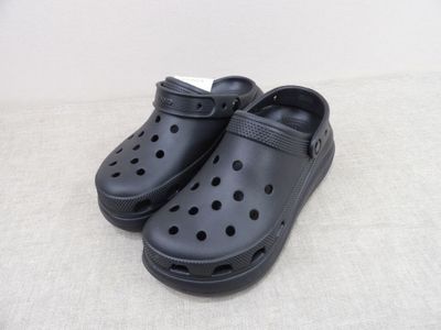 des chaussures Crocs noires percées de trous, posées sur une surface blanche