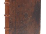 un vieux livre à la couverture brune posé sur une surface blanche