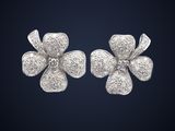 une paire de boucles d'oreilles en forme de fleurs argentées sur fond bleu