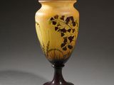yellow and brown vase sitting on top of a table next to a gray wall