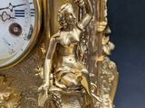 a gold clock with a statue on top of it