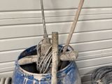 un pot bleu contenant des outils, posé contre un mur