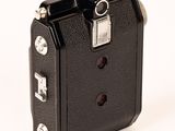 a small black camera with a metal handle on a white surface